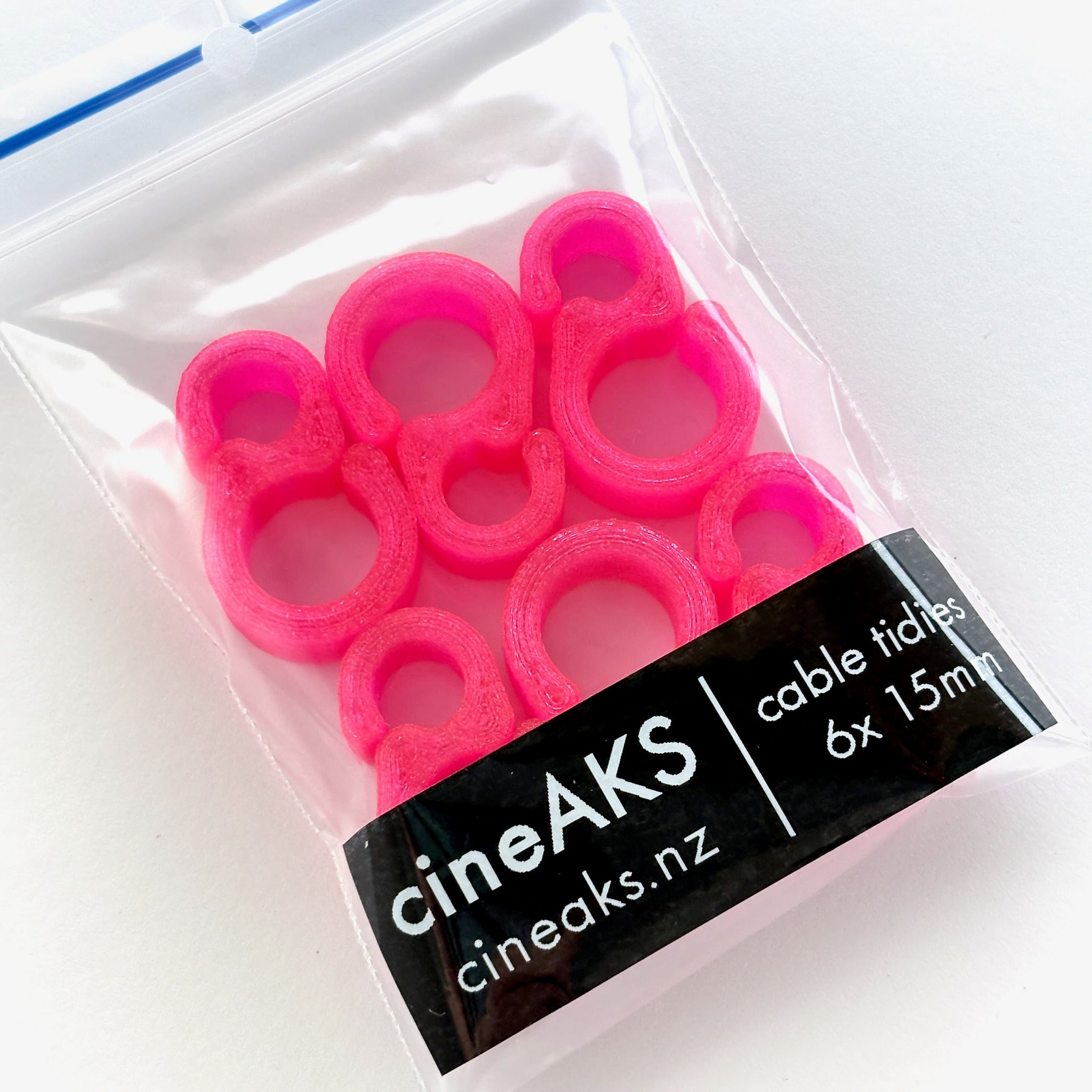 Pack of pink cable tidies with cineAKS branding on a white background
