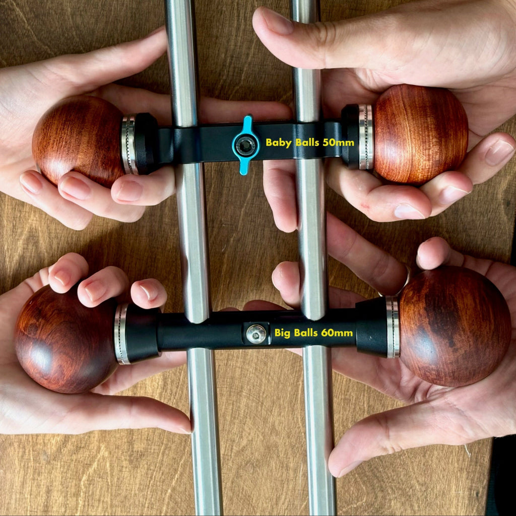 Two pairs of hands holding metal bars with wooden ball camera handles on a wooden surface.