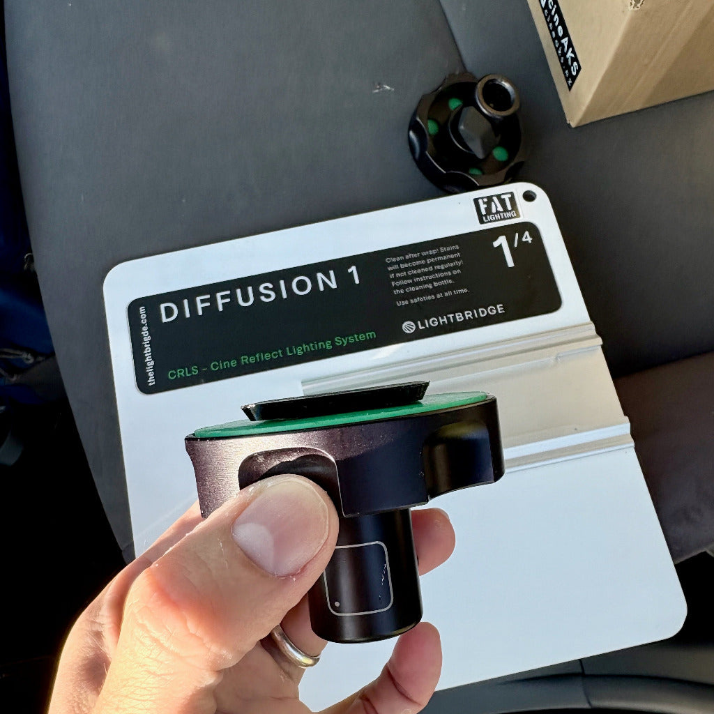 Hand holding a light reflector with 'Lightbridge' branding against a dark background