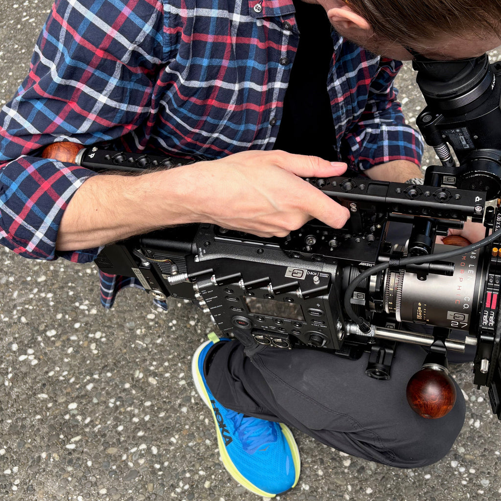 Man holding a Sony Venice camera with wooden ball camera handles and an Atlas Mercury 27mm anamorphic lens.