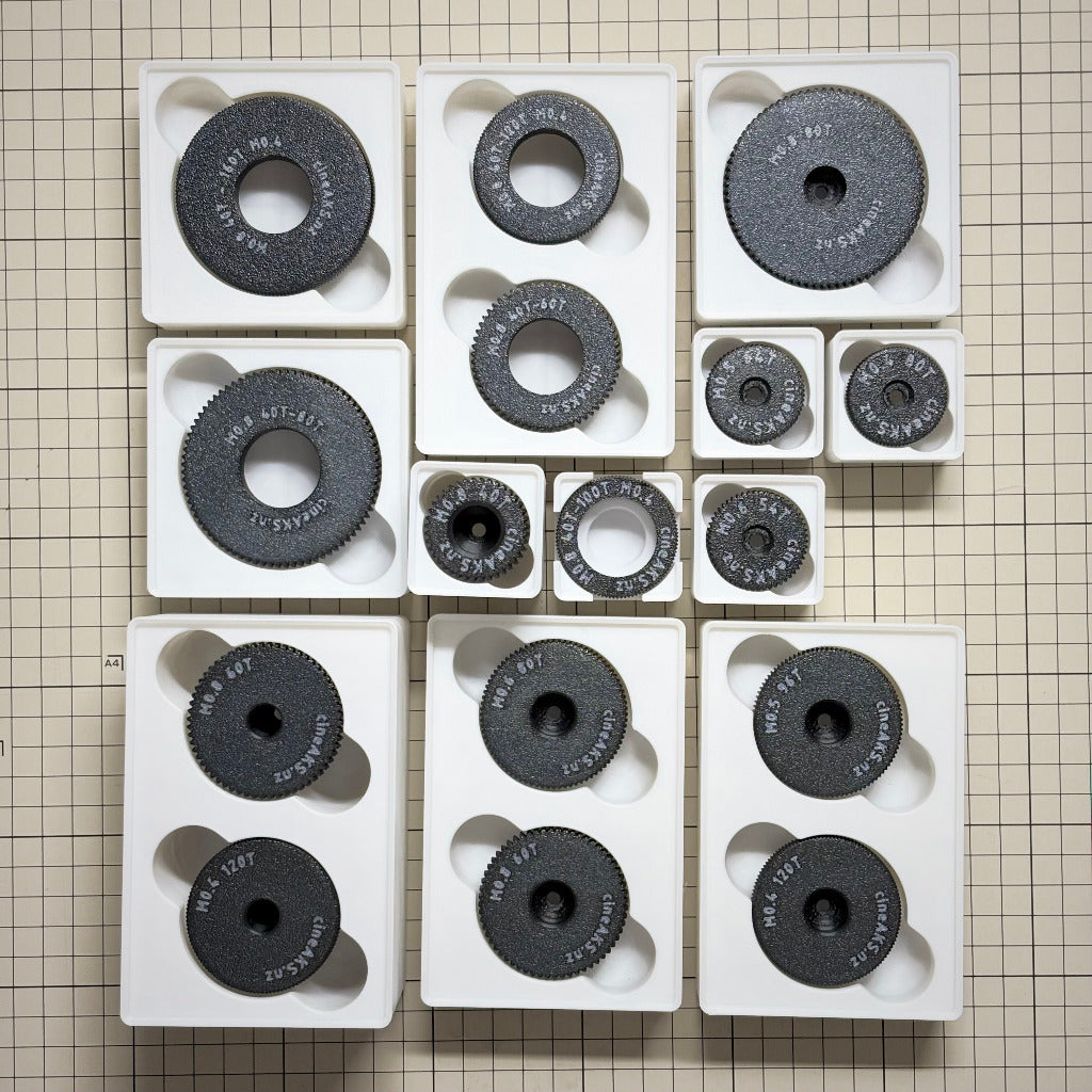 cineAKS cforce Master Collection with 16 cinema lens control gears for arri cforce motors hi5 units, in gridfinity bins, on a beige grid background.
