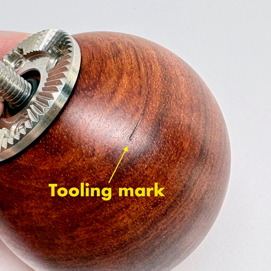 Wooden camera handle with a metal component and 'tooling mark' annotation on a white background