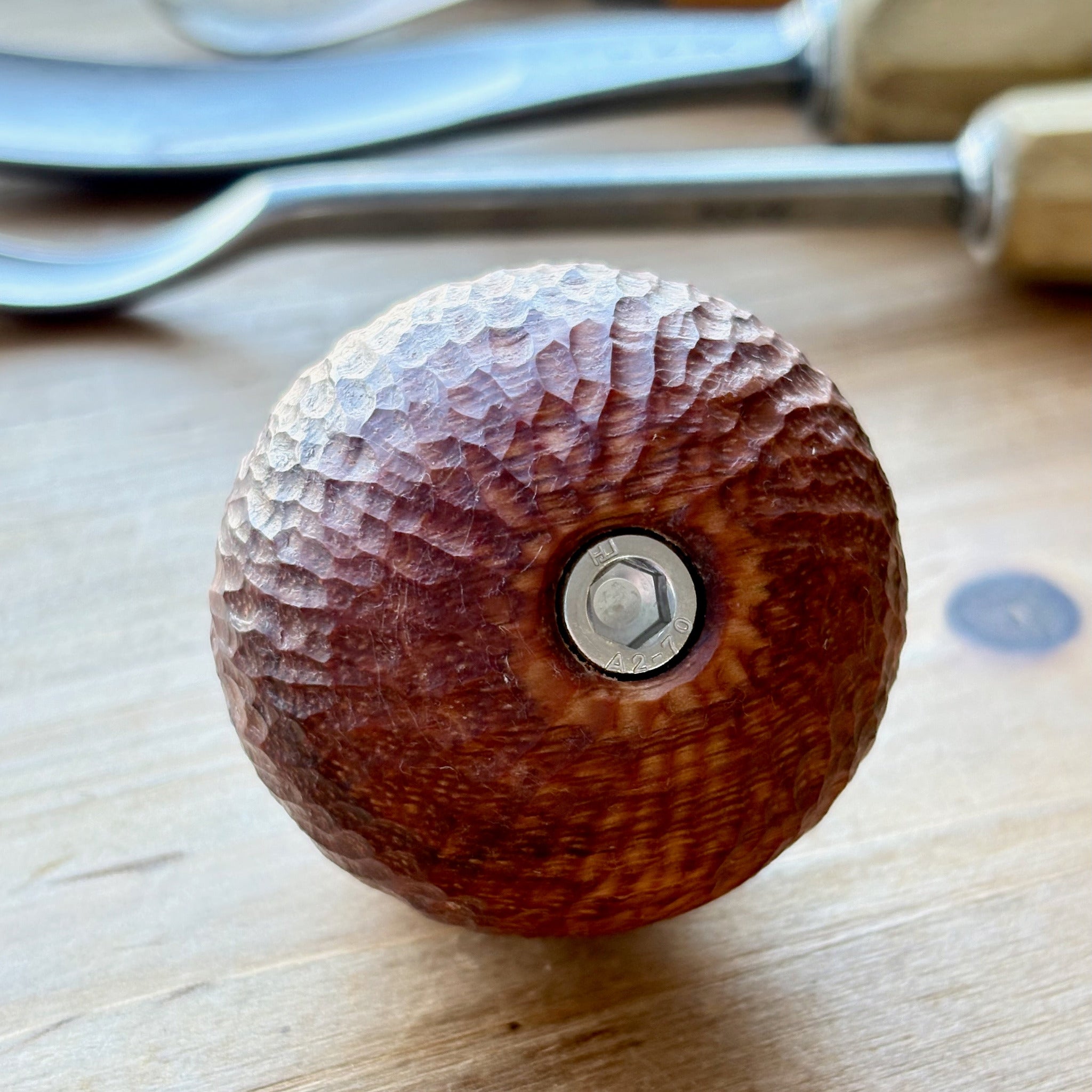 hand carved padauk camera handle with arri rosette on a wooden surface