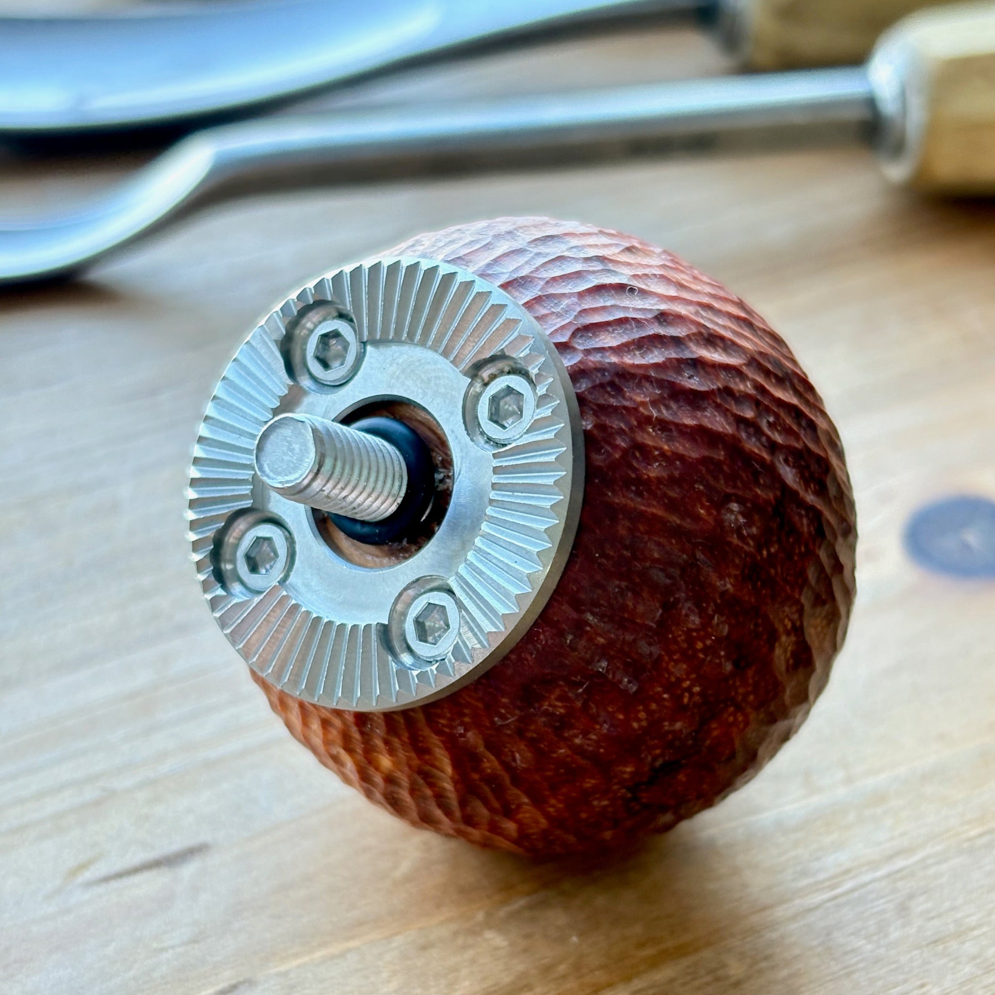 carved wooden camera grip with metal rosette on a wooden surface