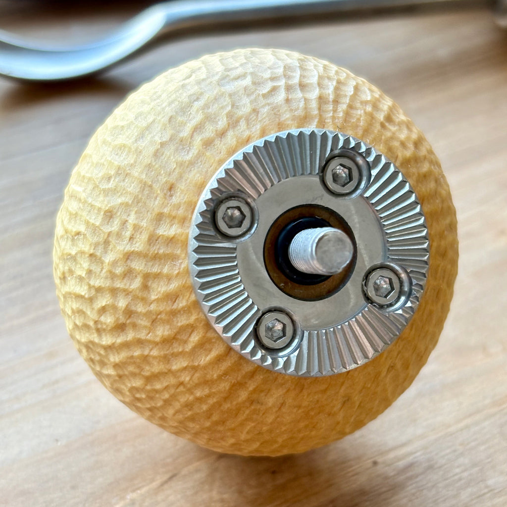 hand carved camera wooden knob handle with metal gear-like center arri rosette on a wooden surface