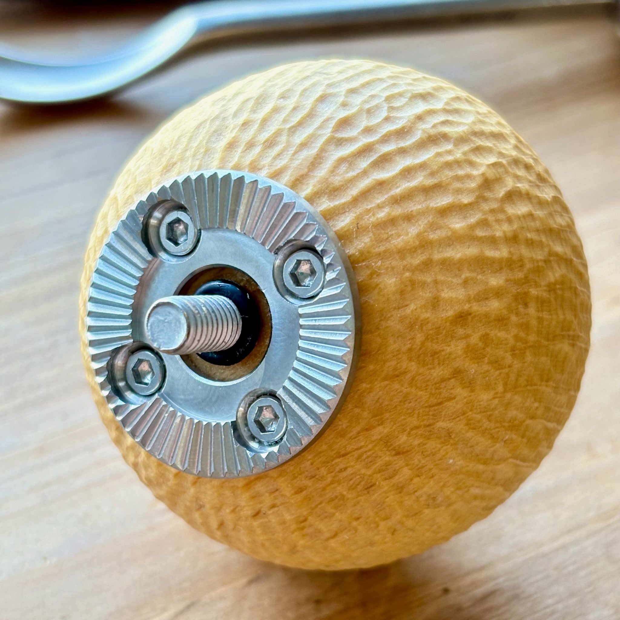 Wooden camera grip hand carved beech with metal rosette on a wooden surface