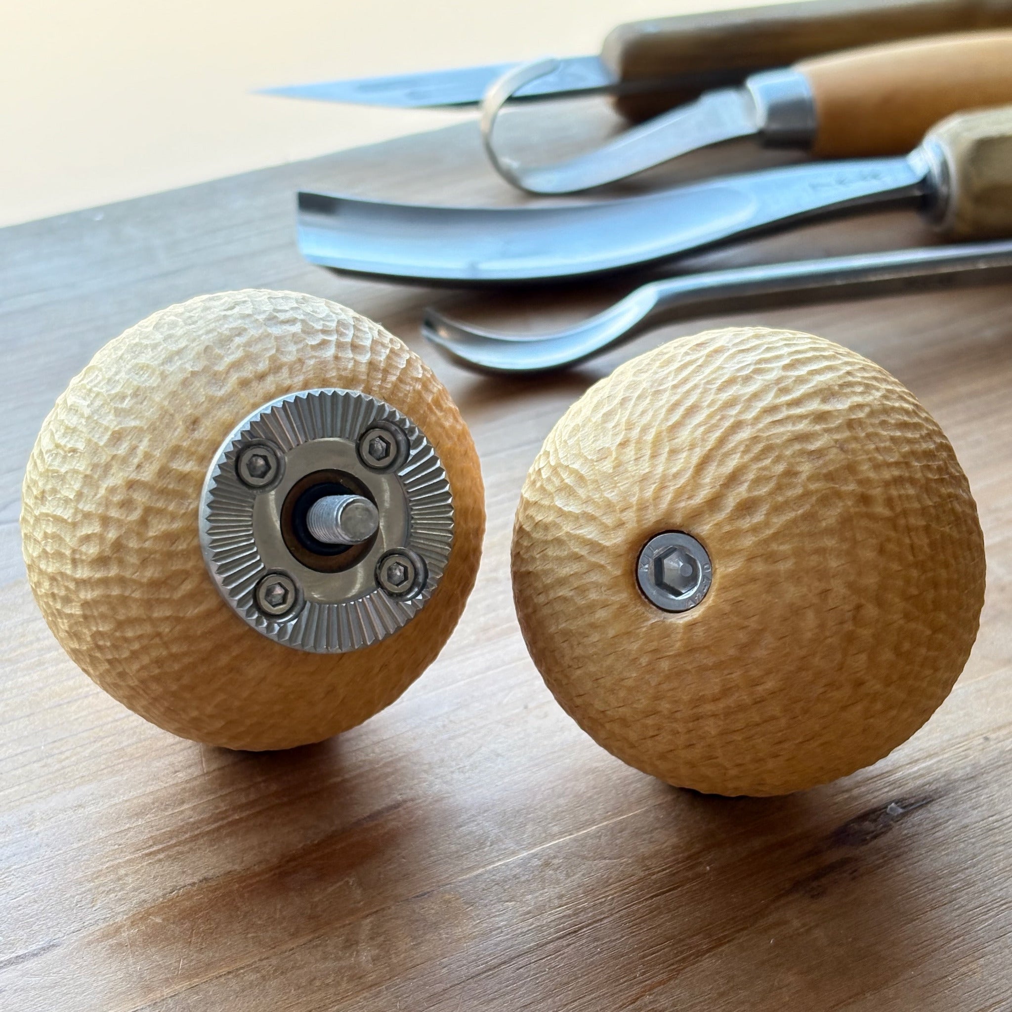Two wooden camera handles from hand carved beech with metal rosette on a wooden surface.