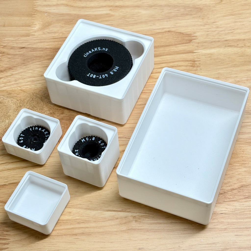 set of white gridfinity bins for arri cforce mini follow focus gears on a wooden surface.