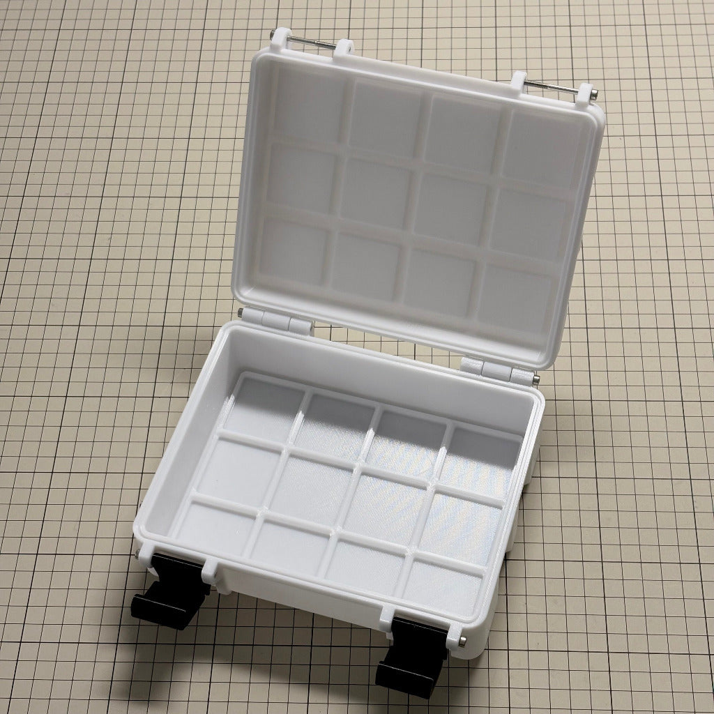 A 3x4x8 Gridfinity case for cineAKS cforce gears with an open lid, featuring a grid compartment pattern inside, resting on a beige grid-patterned surface.