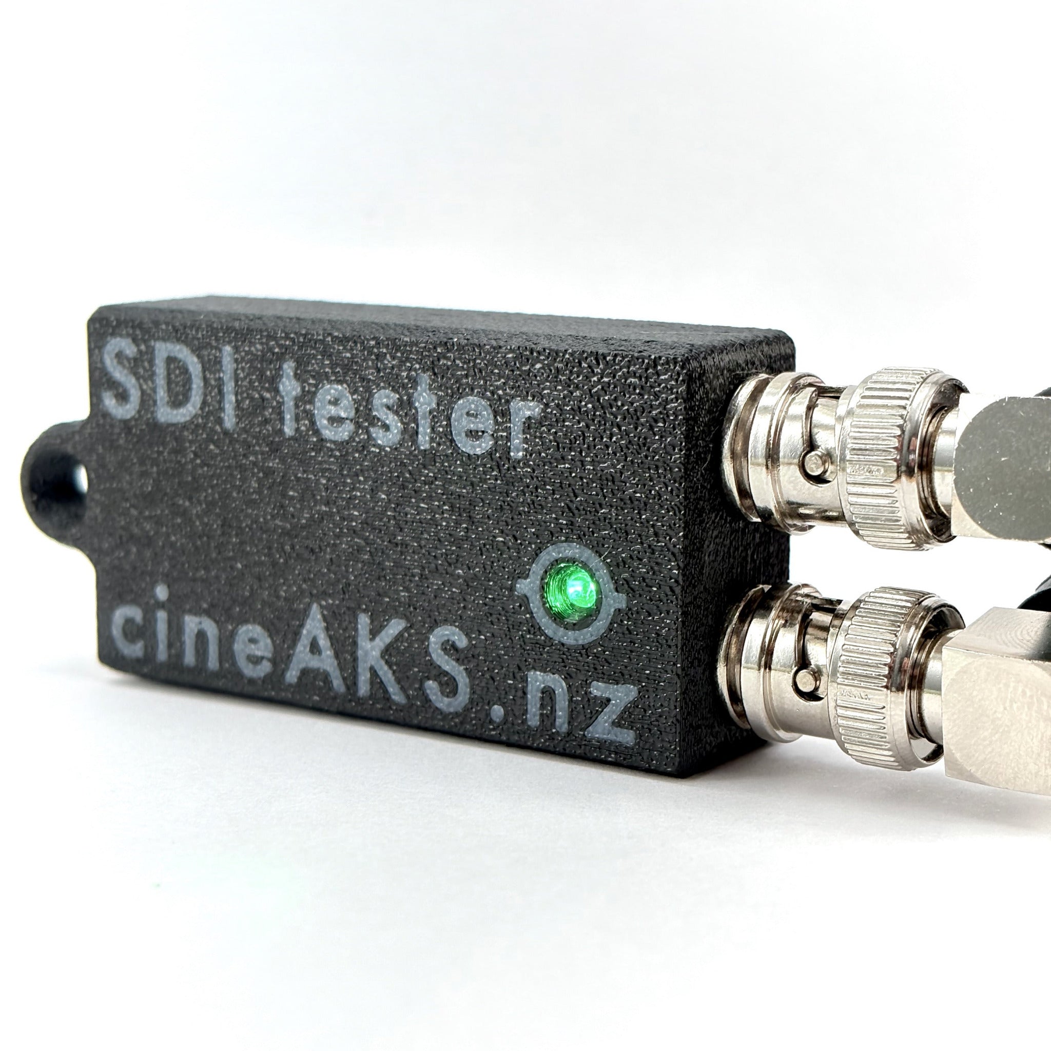 SDI tester with 'cineAKS.nz' branding on a white background