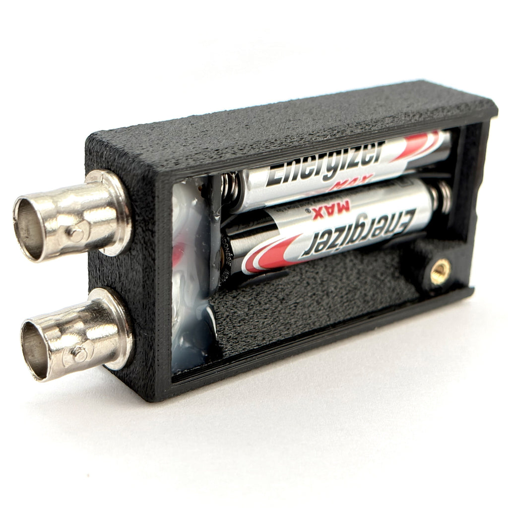 bnc cable continuity tester open showing batteries, on a white background.