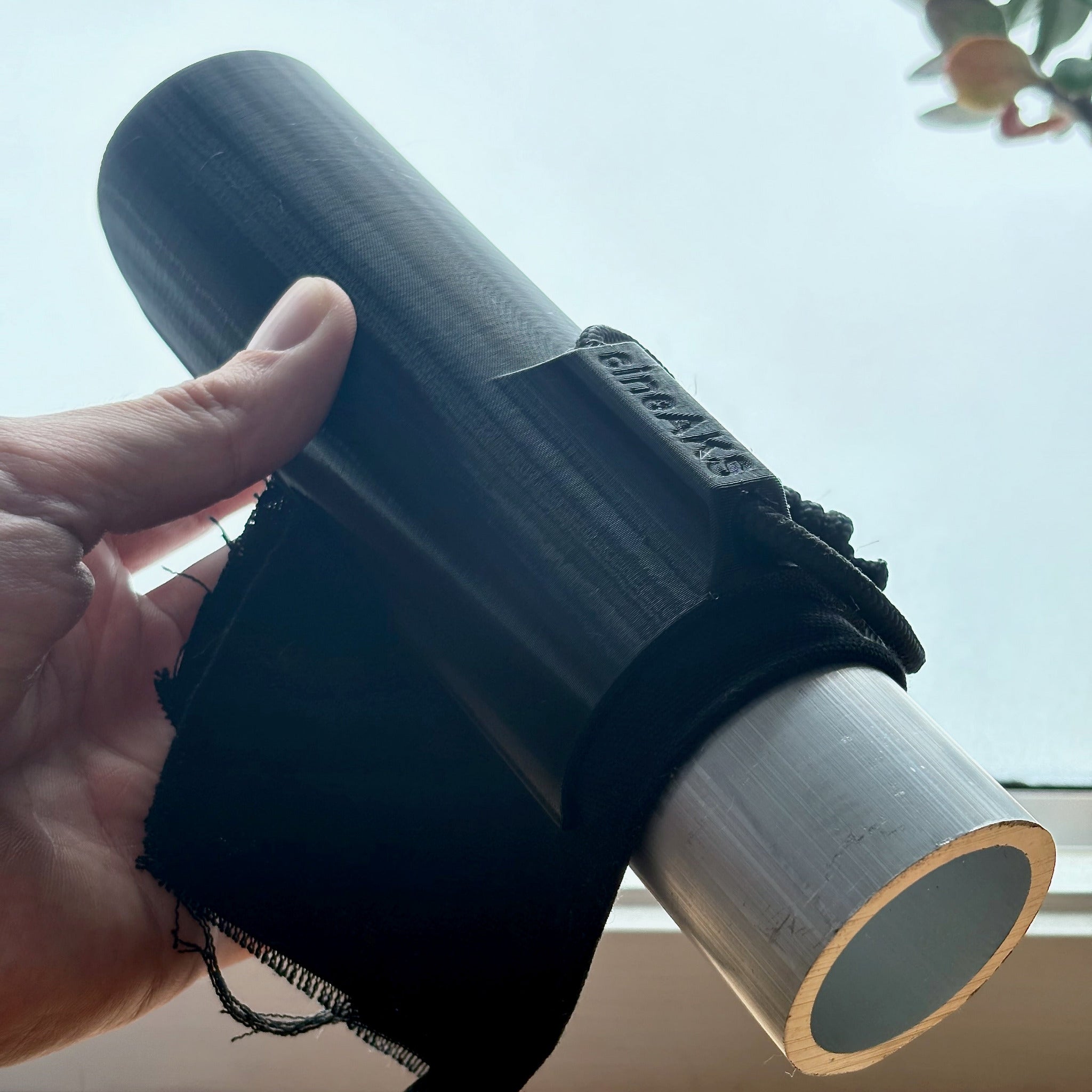 A black speed clip holding a piece of fabric to a length of speed rail scaff pipe.